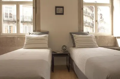 two beds in a room with two windows at Taipas Plaza @ Historical Center in Porto