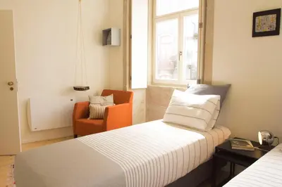 a hotel room with a bed and an orange chair at Taipas Plaza @ Historical Center in Porto