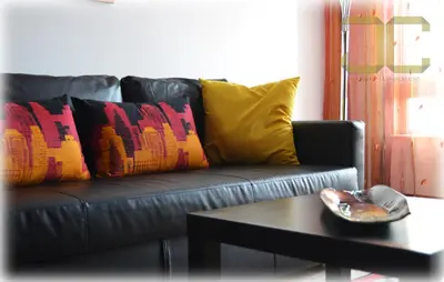 a black leather couch with colorful pillows and a coffee table at Learn Porto Apartment by JC in Porto