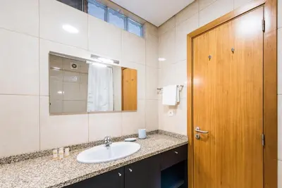 a bathroom with a sink and a wooden door at GuestReady - Ao Coliseu in Porto