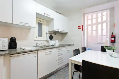 a kitchen with white cabinets and a white table at Home @ Porto Clérigos Apartment in Porto