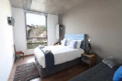 a bedroom with a bed and a couch and a window at Bridge It - Suites & Views in Vila Nova de Gaia
