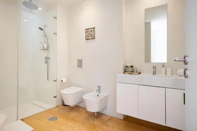 a white bathroom with a toilet and a sink at Blue House Porto Apartments - Parking in Porto