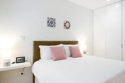 a bedroom with a large white bed with pink pillows at Blue House Porto Apartments - Parking in Porto