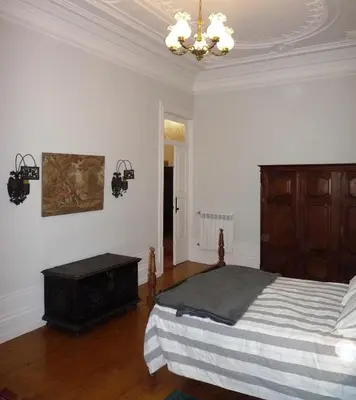 a bedroom with a bed and a chandelier at Casa Familiar do Porto in Porto
