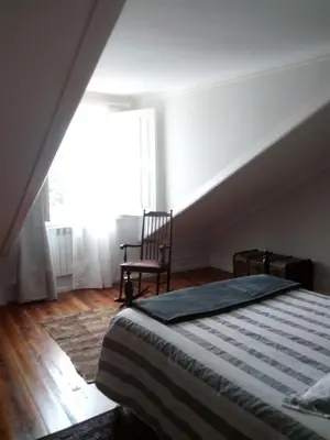 a bedroom with a bed and a chair and a window at Casa Familiar do Porto in Porto