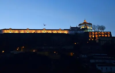 a building on top of a hill at night at RVA - Gustave Eiffel Apartments in Porto