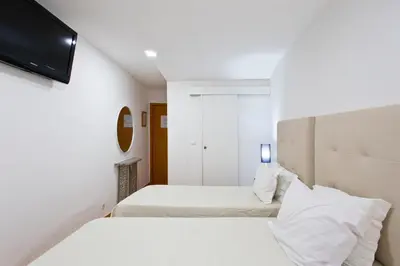 a bedroom with two beds and a flat screen tv at Braganca Oporto in Porto