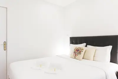 a white bed with a black headboard and white pillows at APOSENTUS - Your Home in Martires da Liberdade in Porto