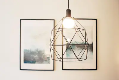 a pendant light hanging in front of three pictures at HM - Carlos Alberto Apartment 2 in Porto