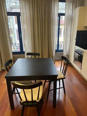 a black table and chairs in a room with windows at Sao Bento Studio in Porto