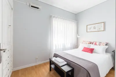 a white bedroom with a white bed with red pillows at Gaia Metro-2 Bedrooms in Vila Nova de Gaia
