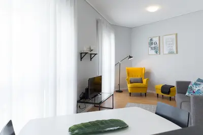 a living room with a table and a yellow chair at Gaia Metro-2 Bedrooms in Vila Nova de Gaia
