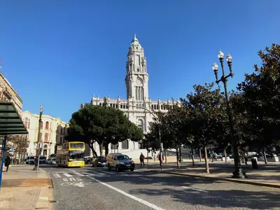 a large building with a clock tower on a city street at HOMEinTOWN Camões - Modern and Quiet Central Studio - AC & Fast WiFi Near Trindade Metro Station in Porto