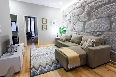 a living room with a couch and a stone wall at Oporto City View - Santo Ildefonso Lovely in Porto