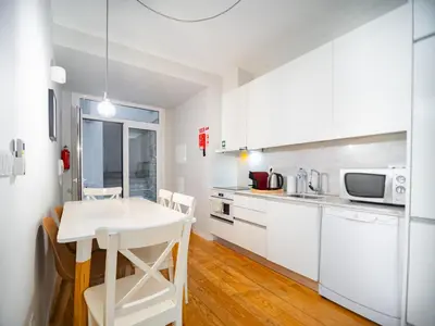 a kitchen with white cabinets and a white table and chairs at Oporto City View - Santo Ildefonso Lovely in Porto