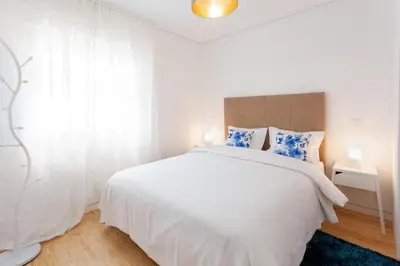 a white bedroom with a large white bed with blue pillows at Urban Views Townhouse Arrábida in Porto