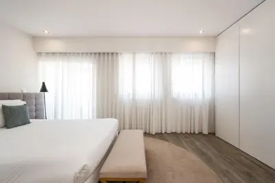 a bedroom with a large bed and white curtains at Ribeira Apartments Santa Catarina in Porto