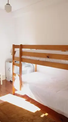 a bedroom with a wooden bunk bed with white sheets at BS Villas Porto in Porto