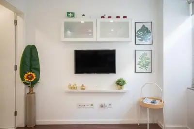 a living room with a tv on a white wall at Central Luxury apartment w AC Downtown and Metro in Porto