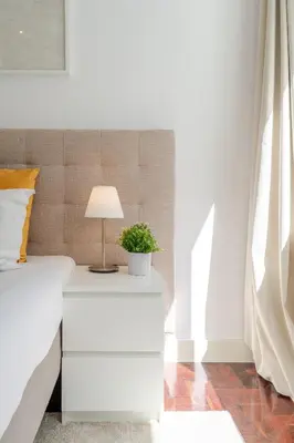 a bedside table with a lamp and a plant on it at Renovated & Quiet 1-Bedroom in Santa Catarina in Porto