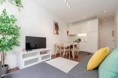 a living room with a couch and a tv and a kitchen at Renovated & Quiet 1-Bedroom in Santa Catarina in Porto