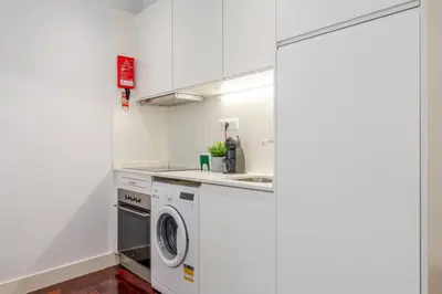 a white kitchen with a washer and dryer at Renovated & Quiet 1-Bedroom in Santa Catarina in Porto