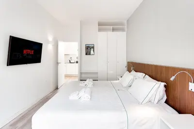 a bedroom with a bed with white sheets and a tv at Central Porto 1BR Apartment - Oporto Bridges in Porto