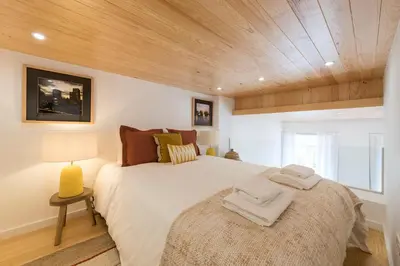 a bedroom with a large bed with a wooden ceiling at BmyGuest Collection - Downtown Mezzanine Apartment in Porto