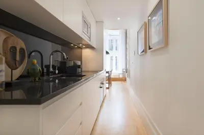 a kitchen with white cabinets and a black counter top at BmyGuest Collection - Downtown Mezzanine Apartment in Porto