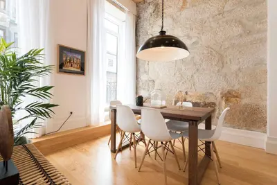 a dining room with a wooden table and white chairs at BmyGuest Collection - Downtown Mezzanine Apartment in Porto