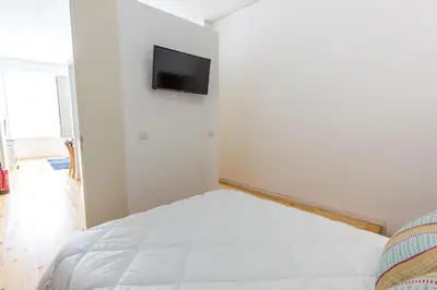 a bedroom with a white bed and a tv on the wall at Downtown Porto Bonfim Studio Apt in Porto