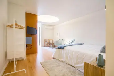 a bedroom with a white bed and a dining room at Republica Apartments at D. Luis I Bridge in Vila Nova de Gaia
