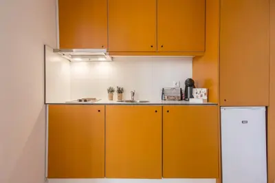 a kitchen with orange cabinets and a sink at Republica Apartments at D. Luis I Bridge in Vila Nova de Gaia