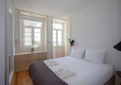 a white bed in a room with two windows at Liiiving in Porto | Central Secret Balcony in Porto
