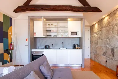 a kitchen with white cabinets and a stone wall at LovelyStay - Dirk Apartment - Almada 4º F in Porto