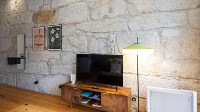 a living room with a stone wall with a television at LovelyStay - Allderman Apartment - Almada 3º F in Porto