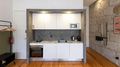 a kitchen with white cabinets and a brick wall at LovelyStay - Allderman Apartment - Almada 3º F in Porto