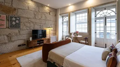 a bedroom with a bed and a stone wall at LovelyStay - Allderman Apartment - Almada 3º F in Porto