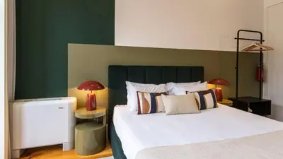 a bedroom with a white bed with a green accent wall at LovelyStay - Allderman Apartment - Almada 3º F in Porto