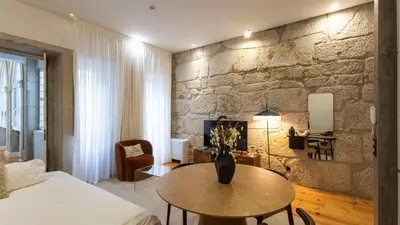 a bedroom with a table and a stone wall at LovelyStay - Allderman Apartment - Almada 1º T in Porto