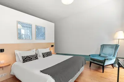 a bedroom with a bed and a blue chair at OX Apartments B Places in Porto