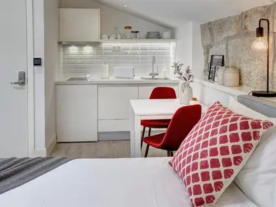 a bedroom with a bed and a table and a kitchen at ApartmentsPorto - Bombarda 451 in Porto