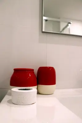 two red and white containers sitting on a bathroom sink at Porto Patricio Apartments in Porto