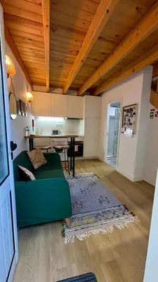 a living room with a green couch and a kitchen at Mezzanine cozy house in Porto