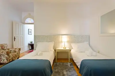 a bedroom with two beds and a chair at Casa Portugueza Experience in Porto