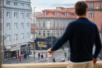 a woman standing on a balcony looking at a city street at Moov Hotel Porto Centro in Porto