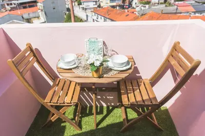 a table on a balcony with two chairs and flowers at APOSENTUS - Your home with a remarkable view in Vila Nova de Gaia