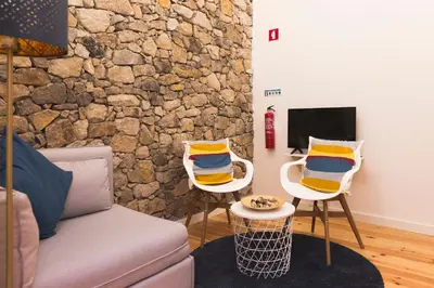 a living room with two chairs and a stone wall at APOSENTUS - Your home with a remarkable view in Vila Nova de Gaia
