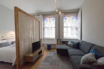 a living room with a couch and a bed and windows at charm in C - Porto Center Apartment in Porto